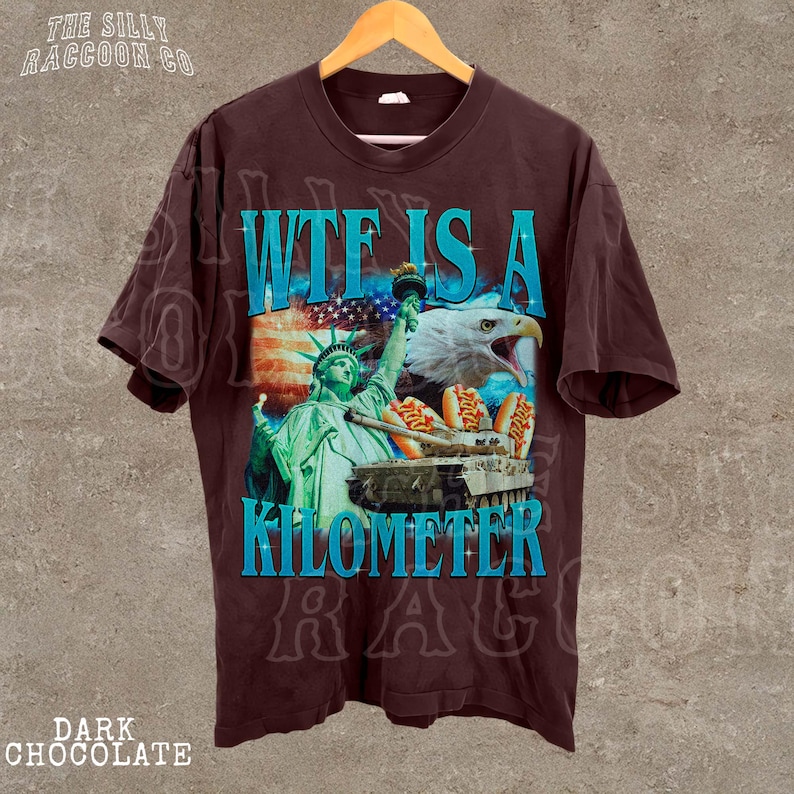 A brown t-shirt with a graphic design featuring the Statue of Liberty and an eagle, along with the text "WTE IS A KILOMETER" and "DARK CHOCOLATE" printed on it.