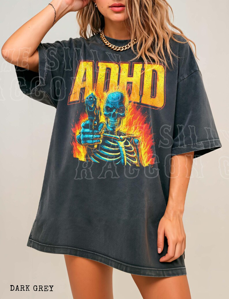 A woman wearing a black t-shirt with a graphic design featuring a skeleton holding a gun and flames.