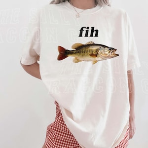A woman wearing a white t-shirt with a fish graphic and red and white checkered shorts.