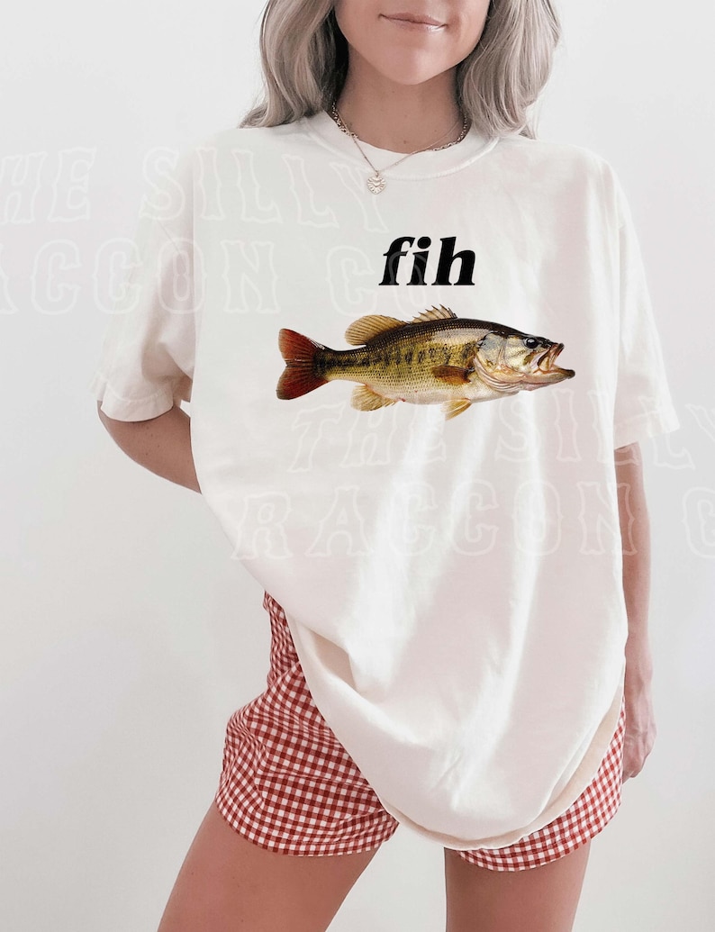 A woman wearing a white t-shirt with a fish graphic and red and white checkered shorts.