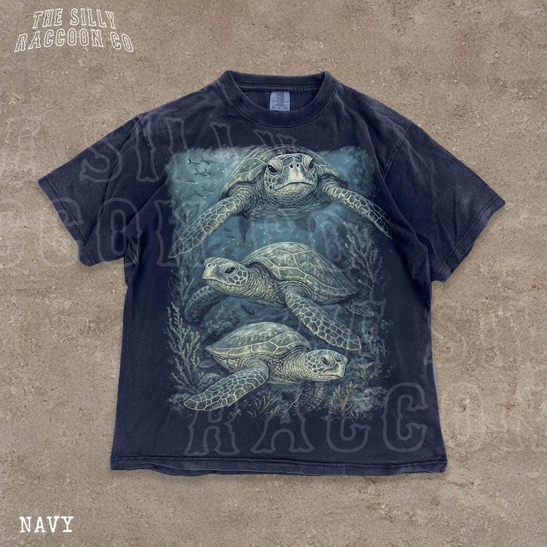 A navy blue t-shirt with a graphic design depicting three sea turtles swimming underwater.