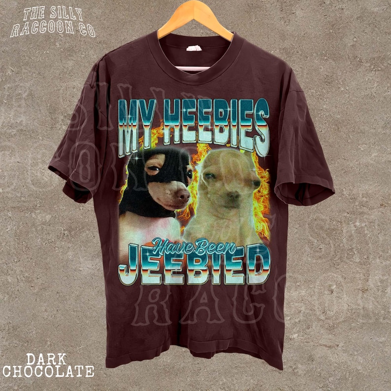 A brown t-shirt with a graphic design featuring two dogs, one black and one tan, along with the text "MY HEEDIES HAVE BEEN JEEBIED" and "DARK CHOCOLATE" printed on it.