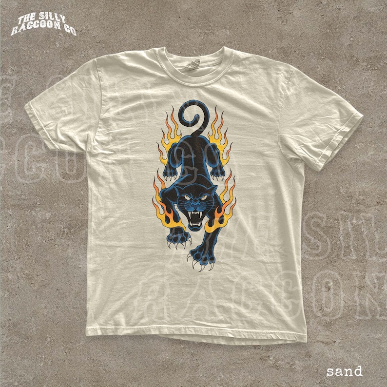 A white t-shirt with a graphic design depicting a black panther with flames surrounding it.