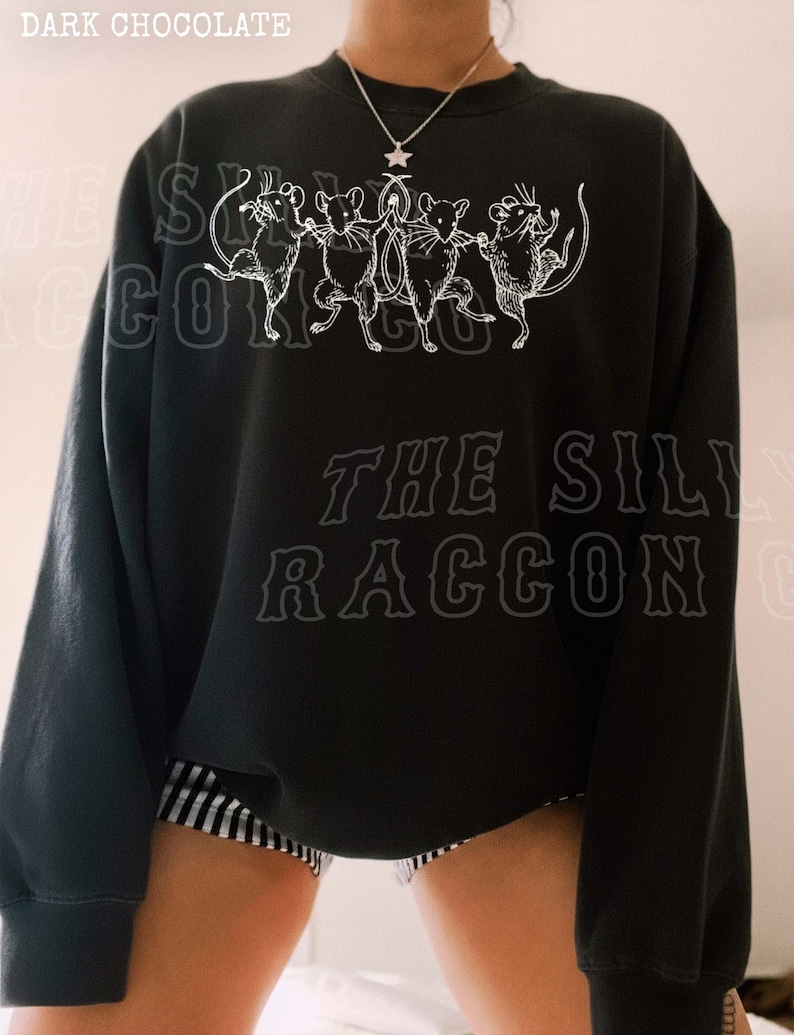 A person wearing a black sweatshirt with a graphic design featuring a group of cats.