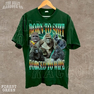 A green t-shirt with a graphic design featuring multiple images of gorillas and the text "Born to SHIT" and "FORCED TO WIDE".