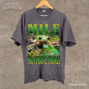 A gray t-shirt with a graphic design featuring a frog and the text "MILF MAN I LOVE FROGS" printed on it.