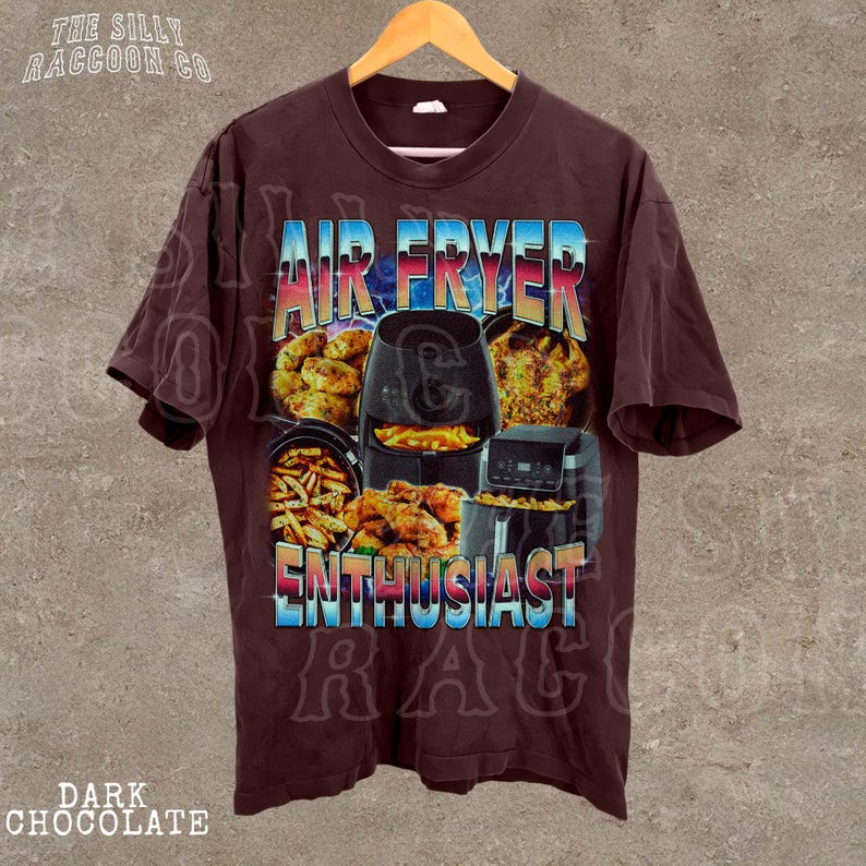 The image is a t-shirt design featuring an air fryer and various fried food items, with the text "AIR FRYER ENTHUSIAST" prominently displayed.