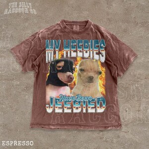 A t-shirt with a graphic design featuring two dogs, one black and one tan, with flames and text overlaying the image.