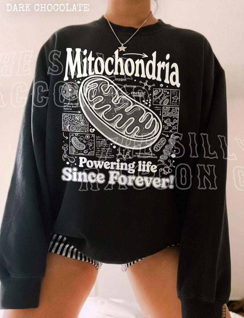a person wearing a black sweatshirt with a graphic design depicting Mitochondria, a cellular organelle, and text that reads "Mitochondria" and "Powering life since forever!".