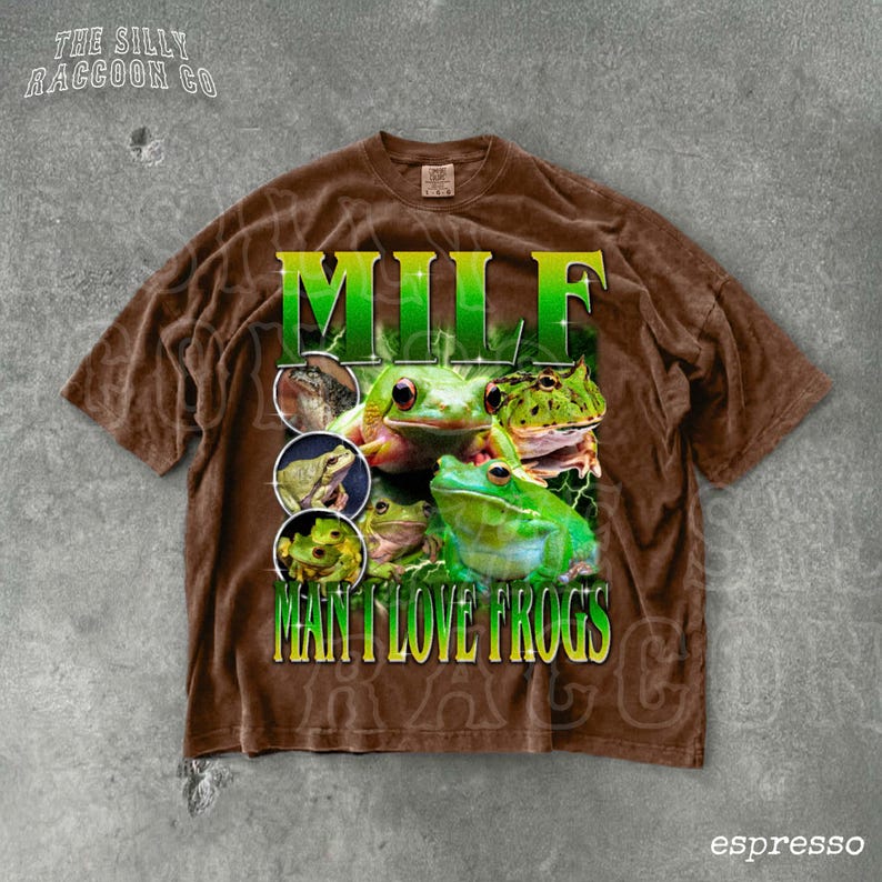 A brown t-shirt with a graphic design featuring multiple images of frogs, along with the text "MILF MAN I LOVE FROGS" printed on it.