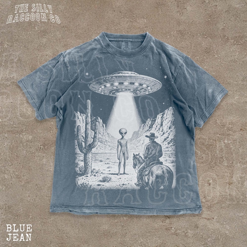The image is a t-shirt design featuring a scene with an alien spacecraft hovering above a desert landscape, where a man on a horse is present.