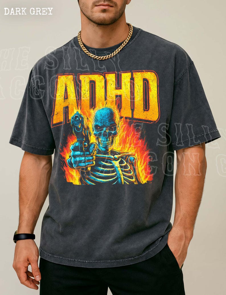 A man wearing a black t-shirt with a graphic design depicting a skeleton holding a gun and surrounded by flames.
