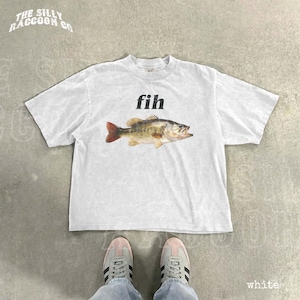 A white t-shirt with a fish graphic printed on it, along with a pair of white sneakers.