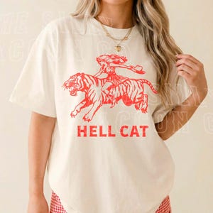 A woman wearing a white t-shirt with a graphic design of a tiger and the text "HELL CAT" printed on it.