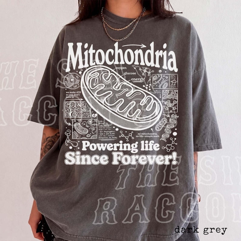 A person wearing a gray t-shirt with a graphic design depicting Mitochondria, a cellular organelle, and text that reads "Mitochondria Powering life Since Forever!".
