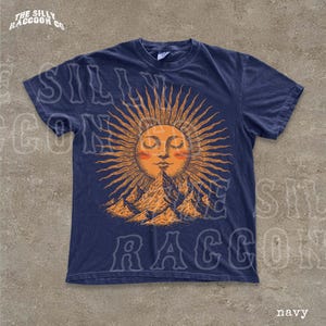 A navy blue t-shirt with a sun and mountain graphic printed on it.