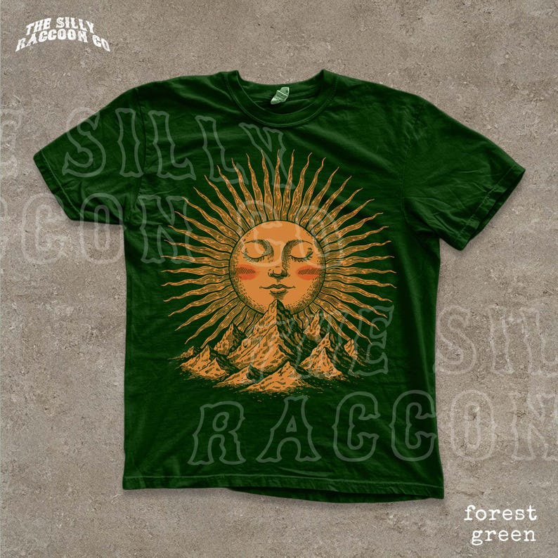 A green t-shirt with a sun design and mountains in the background.