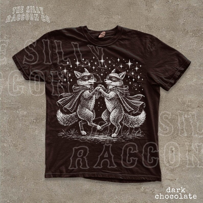 a black t-shirt with a graphic design depicting two foxes dancing together under a starry sky.