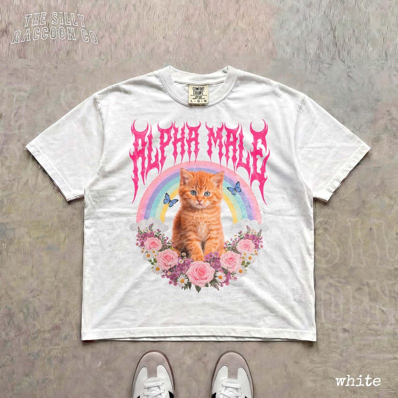 A white t-shirt with a graphic design featuring an orange cat surrounded by flowers and a rainbow.