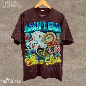 A dark-colored t-shirt with a graphic design featuring casino elements, including a roulette wheel, playing cards, and poker chips.