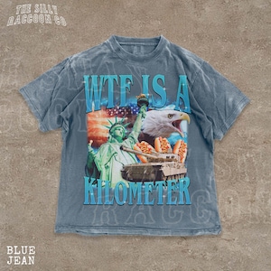 A t-shirt with a graphic design featuring the Statue of Liberty and an eagle, along with the text "WTF IS A KILOMETER" printed on it.