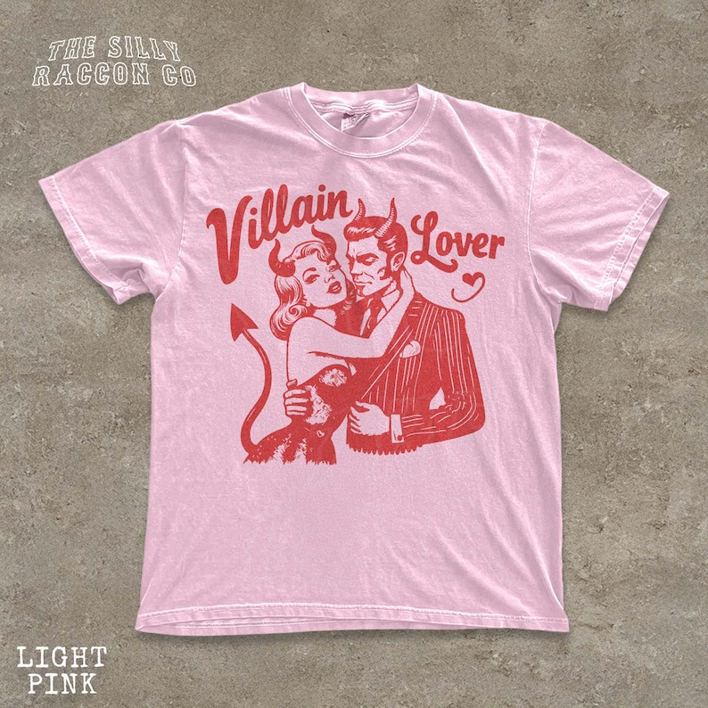 A pink t-shirt with a graphic design depicting a man and a woman embracing, with the text " Villain Lover" above them.