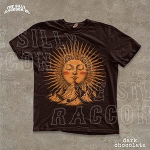 A black t-shirt with a sun and mountain design printed on it.