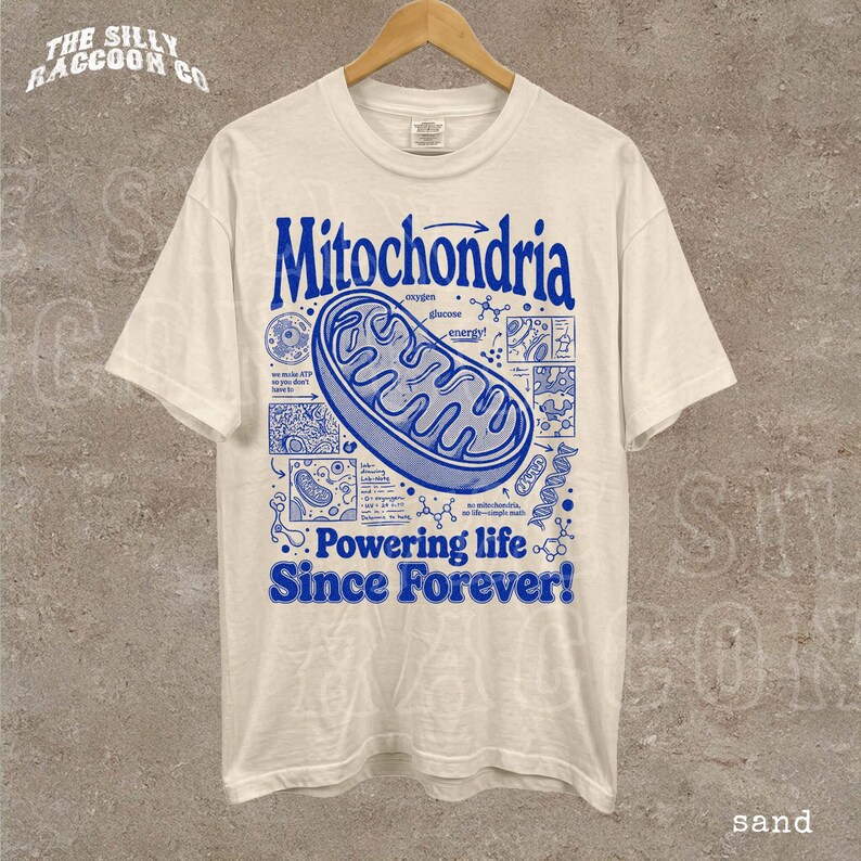 A white t-shirt with a graphic design depicting Mitochondria, a cellular organelle, and text that reads "Mitochondria Powering life Since Forever!"