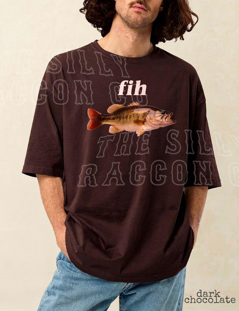 A man wearing a brown t-shirt with a fish graphic and the word "fih" printed on it.
