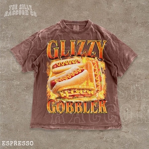 A brown t-shirt with a graphic design featuring two hot dogs on a flame background, along with the text "GLIZZY GOBBLER" and "ESPRESSO".