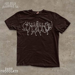 A dark brown t-shirt with a white graphic design depicting a group of cats.