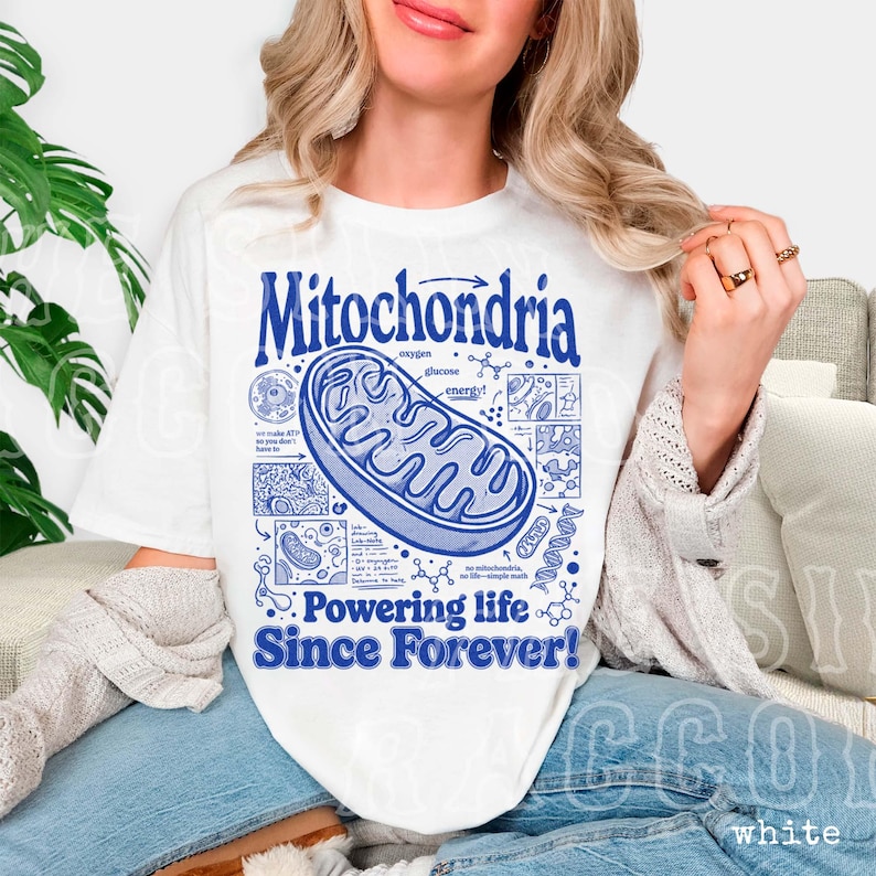 A woman wearing a white t-shirt with a graphic design of Mitochondria, a cellular organelle, and text that says "Mitochondria Powering life Since Forever!".