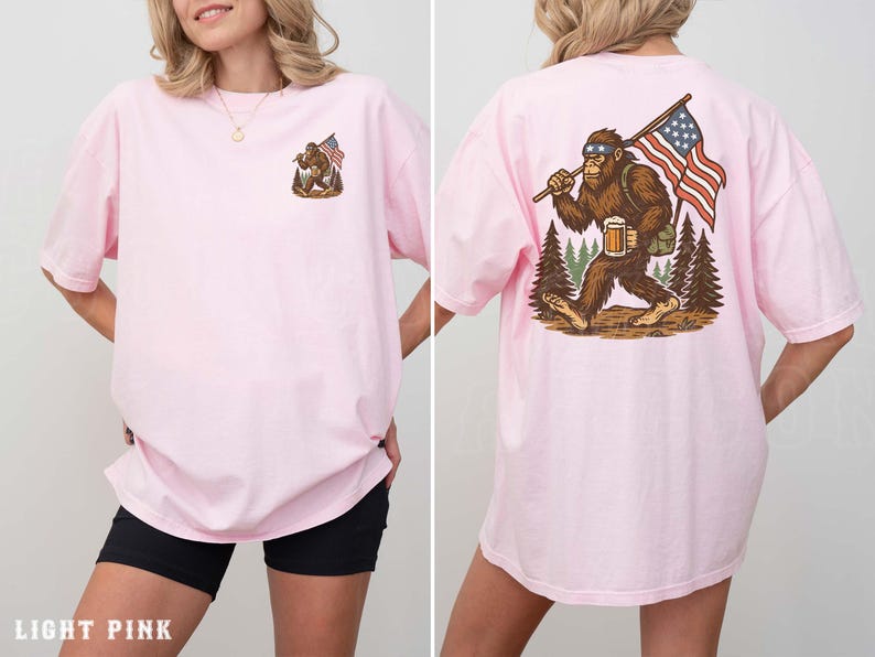 A woman wearing a pink t-shirt with an illustration of a Sasquatch carrying an American flag.
