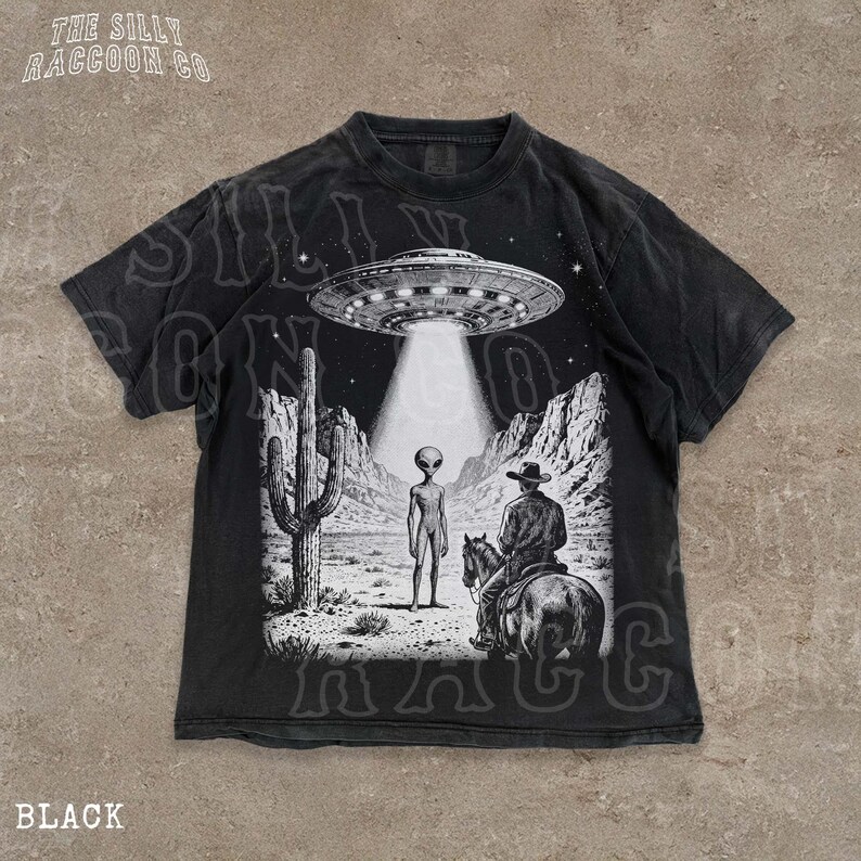 The image is a t-shirt design featuring a scene with an alien spacecraft hovering above a desert landscape, where a man on a horse is present.