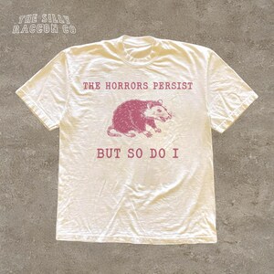 A white t-shirt with a graphic design and text printed on it.