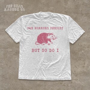 A white t-shirt with a graphic design and text printed on it.