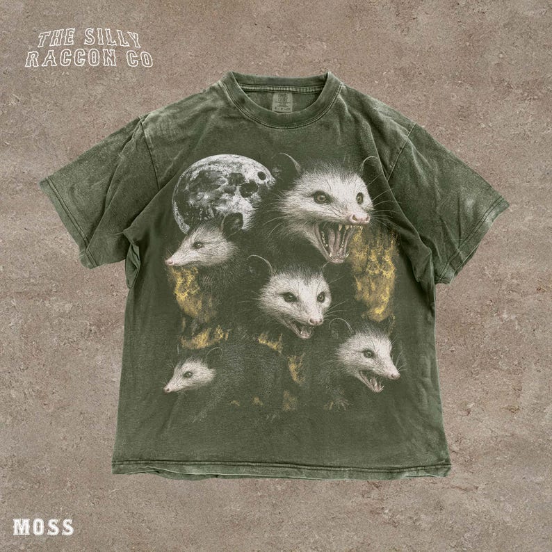 A t-shirt with a graphic design featuring multiple opossum faces with open mouths, arranged in a layered manner.