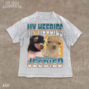 A t-shirt with a graphic design featuring two dogs, one black and one tan, with flames and text overlaying the image.