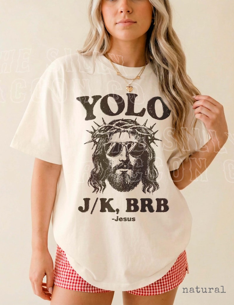A woman wearing a white t-shirt with a graphic of Jesus and text that says "YOLO J/K, BRB - Jesus".