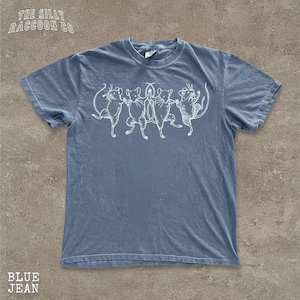 A blue t-shirt with a white graphic design depicting a group of cats dancing together.