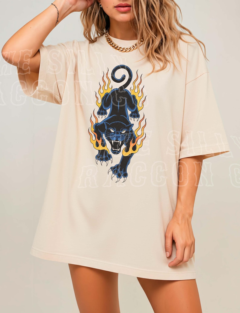 A woman wearing a white t-shirt with a graphic design of a black panther with flames on its back.