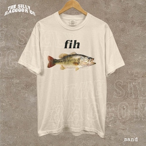 A white t-shirt with a printed image of a fish and the word "fih" printed on it.