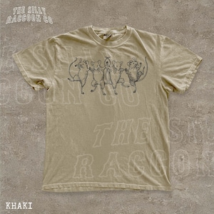 A khaki t-shirt with a graphic design of five cartoon mice dancing together.