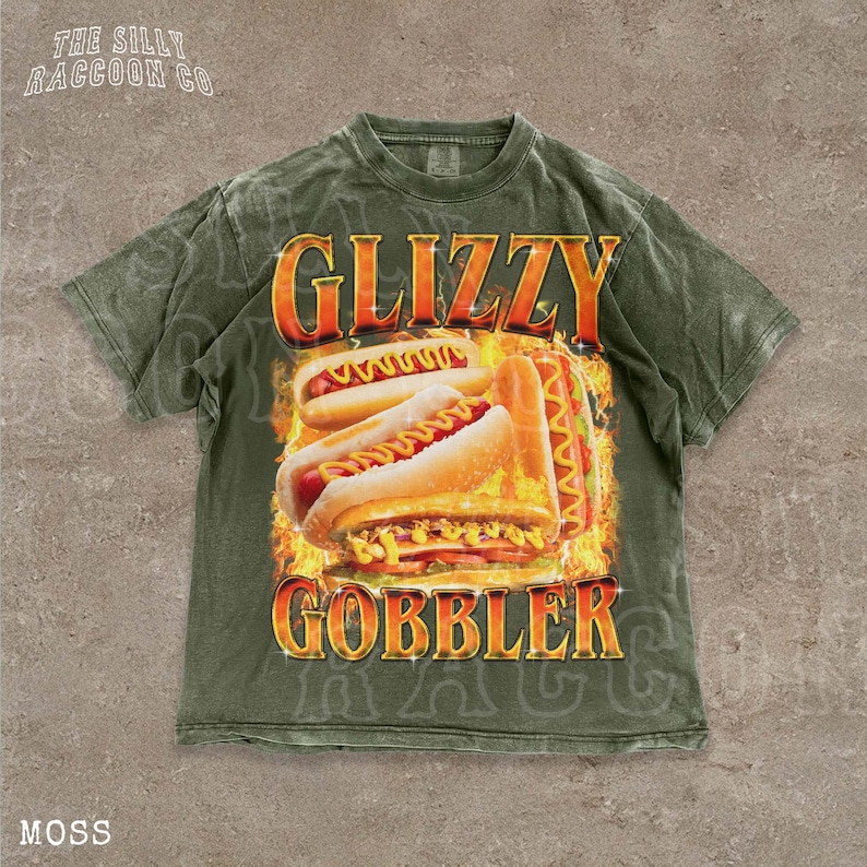 A t-shirt with a graphic design featuring two hot dogs on a bun, with flames around them, and the text "GLIZZY GOBBLER" prominently displayed.