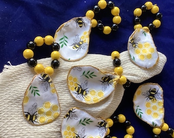 Servilletero con forma de concha de ostra y amuleto de vino con abejas