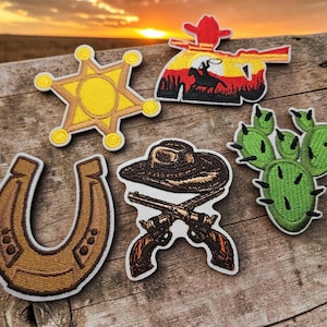 May include: A collection of five embroidered patches featuring a yellow sheriff star, a sunset scene with a cowboy on horseback, a brown horseshoe, a brown cowboy hat crossed with two revolvers, and a green prickly pear cactus with black needles.