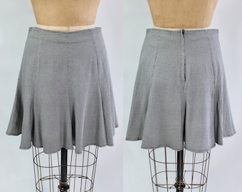 May include: A black and white checkered skirt with a flared silhouette. The skirt is displayed on a mannequin, showcasing its design and fit. The skirt has a zipper closure at the back.