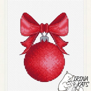 May include: A red Christmas ornament with a large red bow on top. The ornament is decorated with a white pattern.