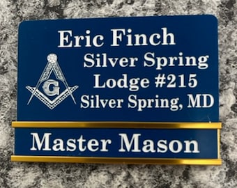 May include: A blue name badge with gold trim, featuring the name "Eric Finch", "Silver Spring Lodge #215", and "Master Mason" in white lettering. The Masonic symbol is also displayed.