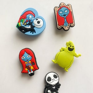 Puede incluir: Colecci&oacute;n de cinco coloridos dijes para zapatos con personajes de "Pesadilla antes de Navidad". Incluye a Jack Skellington, Sally y Oogie Boogie, en varias poses y dise&ntilde;os. Los dijes est&aacute;n hechos de goma o material similar.
